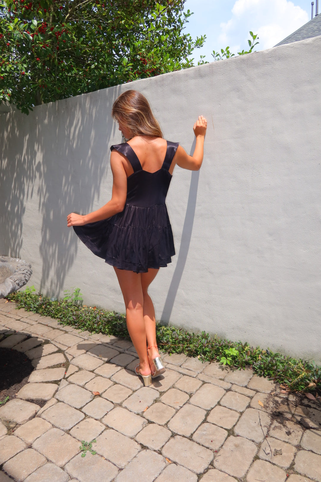 Black satin Biarritz Romper by Strawberry Paris with satin-covered buttons and ruffle accents.